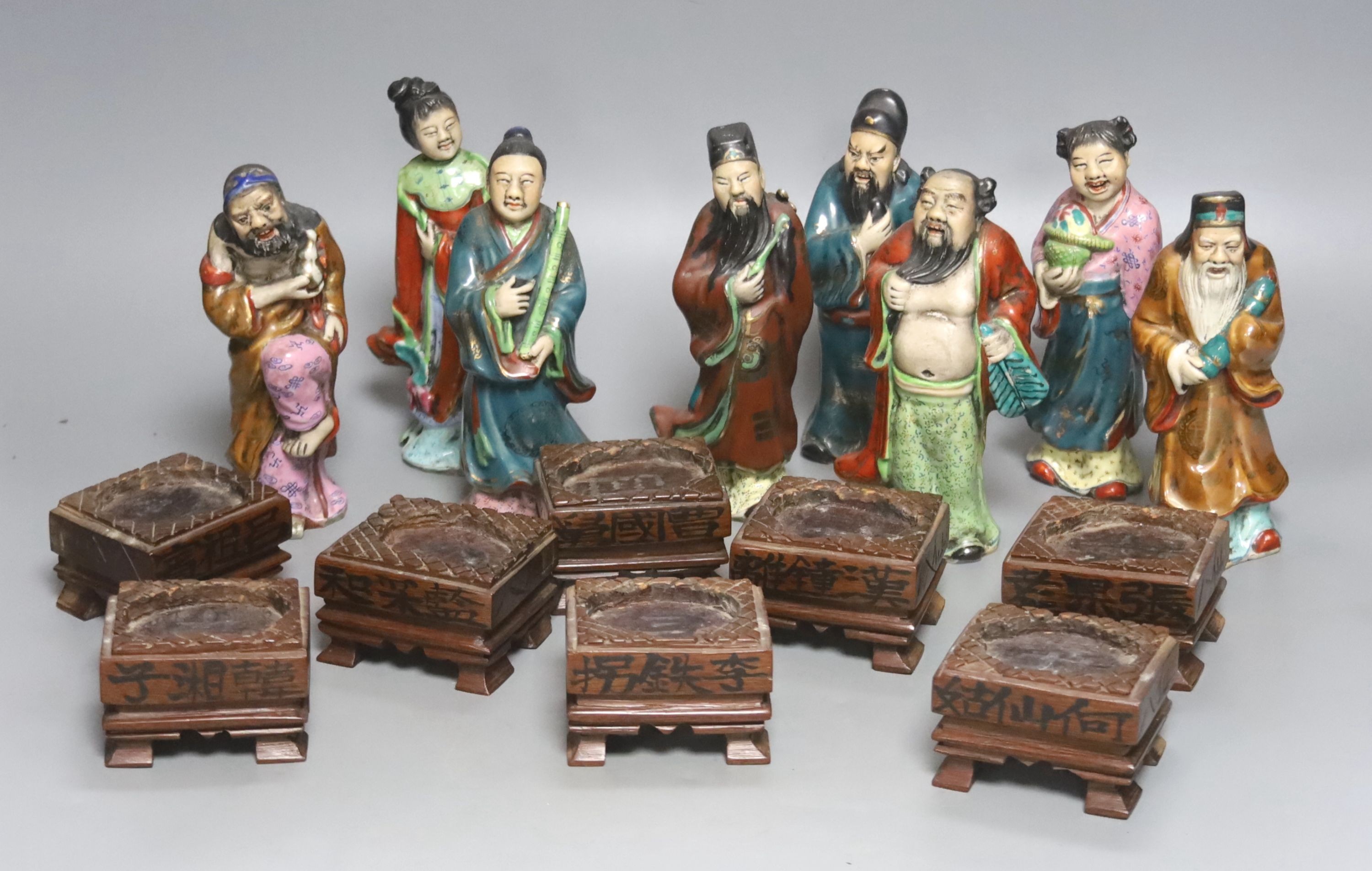 A set of eight 20th century Chinese porcelain figures of immortals, 15cm, each on carved wood stand